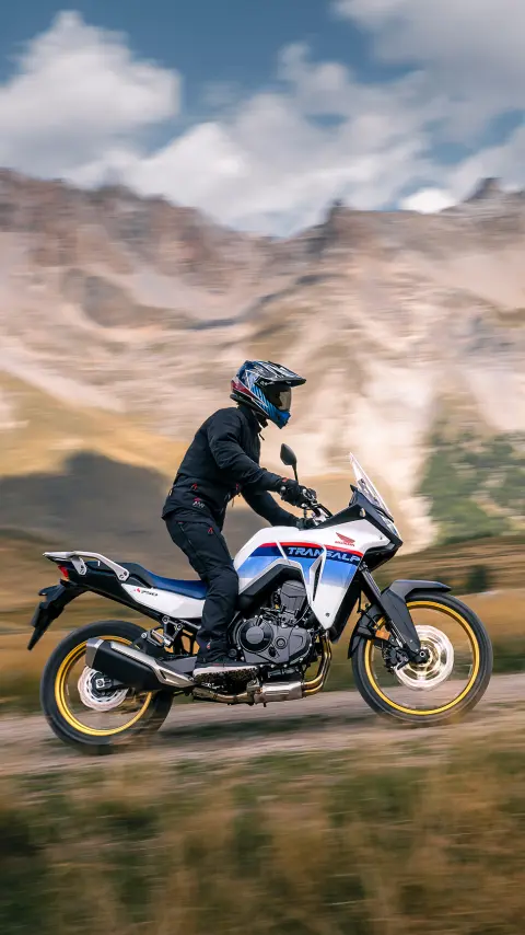 Condutor sobre uma XL750 Transalp em cenário de montanha.