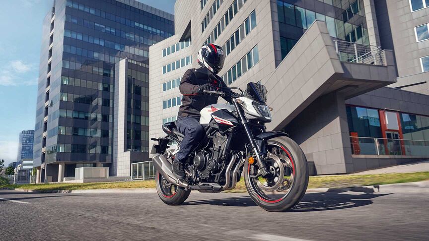 Modelo a conduzir uma moto num cenário urbano.